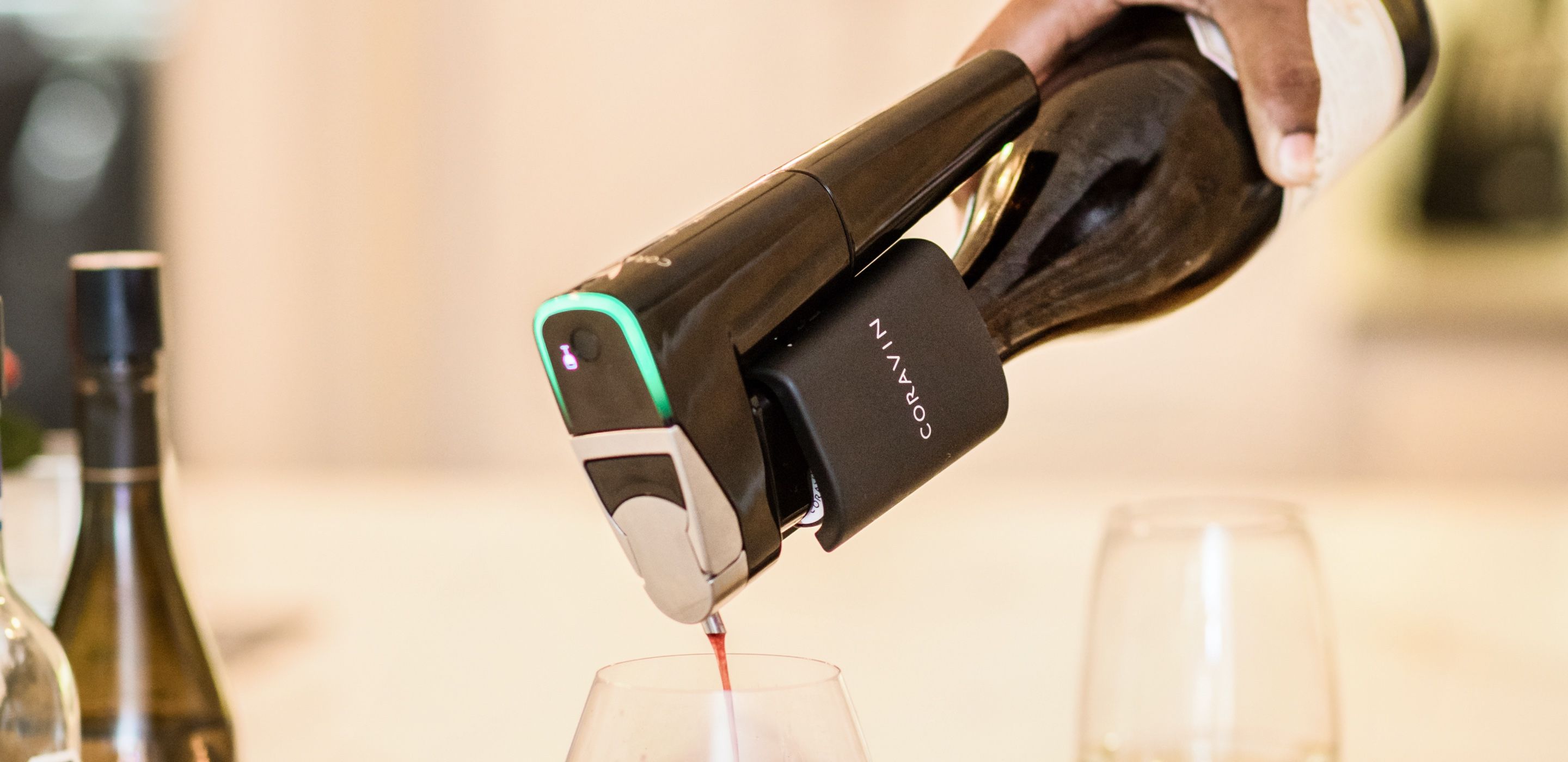 Coravin's wine preservation system on top of a bottle, as a person is pouring wine into a wine glass.